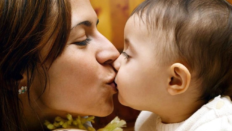 side view of mother kissing and embracing her baby girl, lifestyle shot.