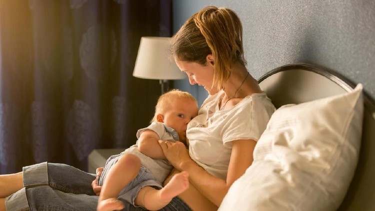 Young mother breastfeeding at home, bonding with baby child toddler