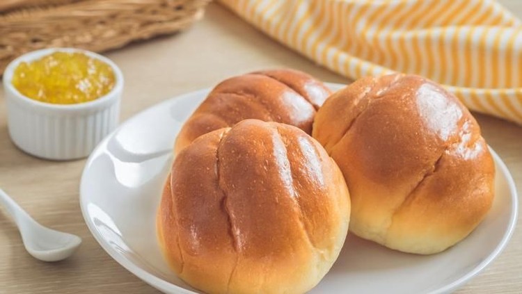 Round bun, bread rolls on white plate and pineapple jam