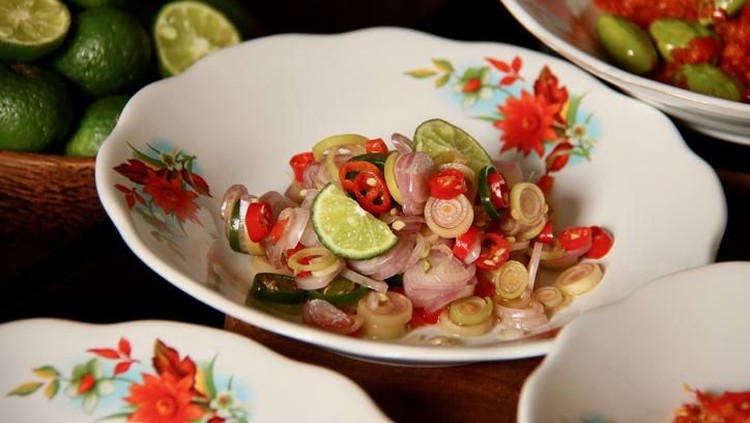 Sambal Matah, a popular salsa condiment of chopped chili peppers with lemon grass and shallots from Bali. The condiment is plated on old-fashioned crockery with red flowers paintings. It is served together with other popular spicy condiments from several other regions in Indonesia.