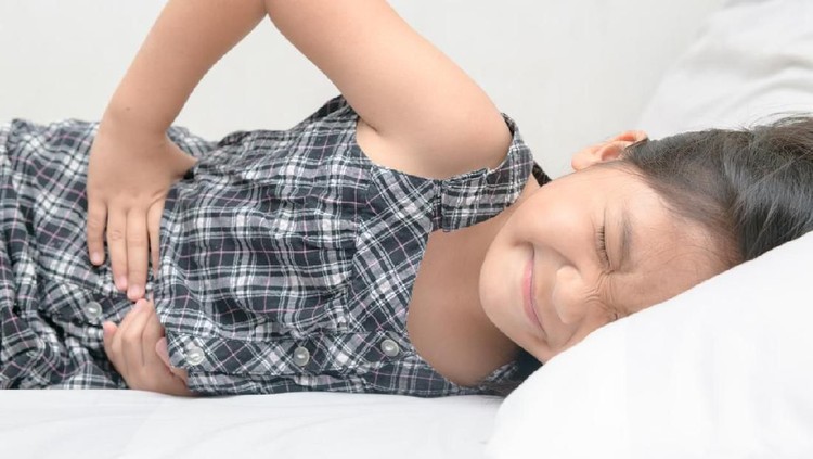 asian child suffering from stomachache and lying on bed. diarrhea or healthy concept