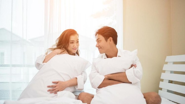Happy young couple is having fun in bed