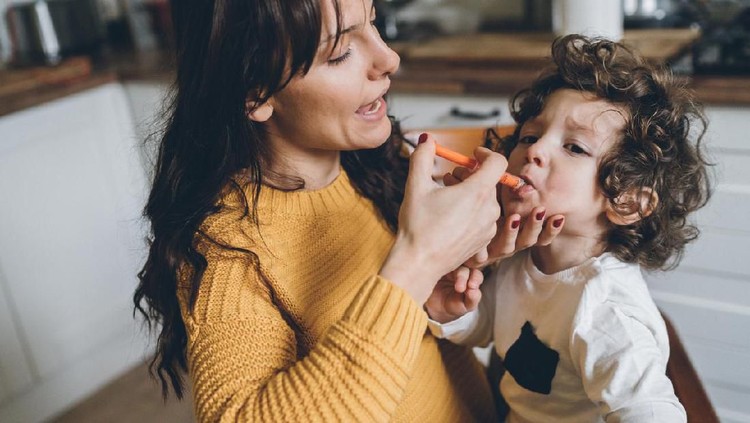 Mother giving syrup with syringe to her cute little son