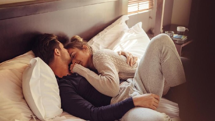 Loving young couple sleeping together in bed. Young man and woman lying together in bedroom.