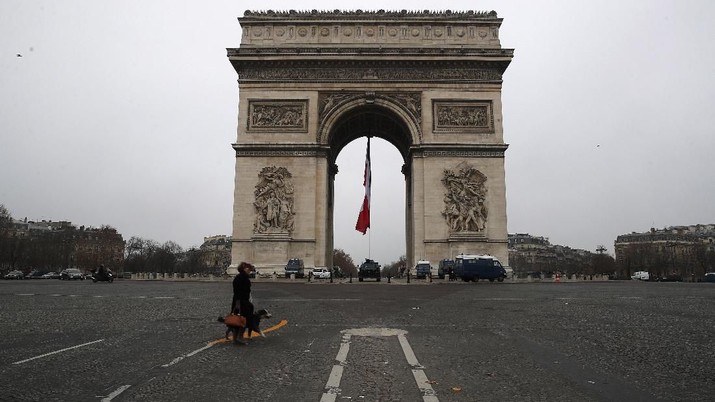 A woman walks her dog on the empty Champs Elysees avenue, with the Arc de Triomphe in background, in Paris, Thursday, Dec. 5, 2019. The Eiffel Tower shut down Thursday, France's vaunted high-speed trains stood still and teachers walked off the job as unions launched nationwide strikes and protests over the government's plan to overhaul the retirement system. (AP Photo/Francois Mori)