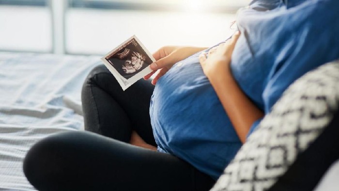 Closeup shot of an unrecognizable pregnant woman holding an ultrasound scan