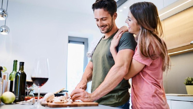 996097574 Loving joyful young couple embracing and cooking together, having fun in the kitchen