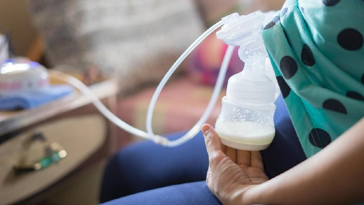Automatic breast pump, mothers breasts milk is the most healthy food for newborn baby. Happy mother with babys at bed room ,home,vintage color