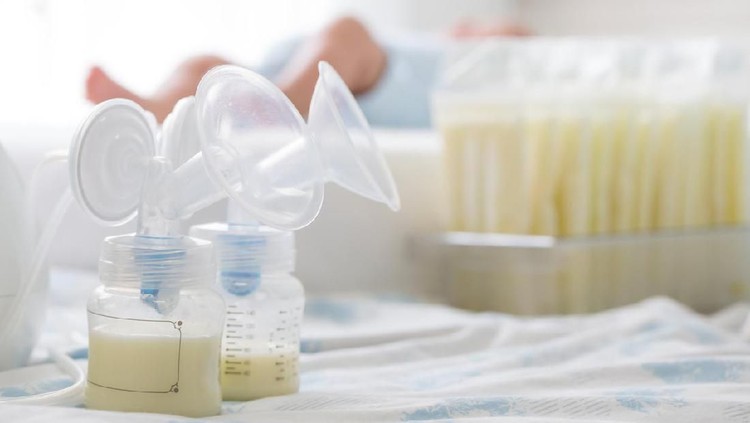 Breast milk frozen in storage bag and baby lying on background