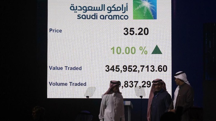 A Saudi stock market official smiles as he watches the stock market screen displaying Saudi Arabia's state-owned oil company Aramco after the debut of Aramco's initial public offering (IPO) on the Riyadh's stock market in Riyadh, Saudi Arabia, Wednesday, Dec. 11, 2019. (AP Photo/Amr Nabil)