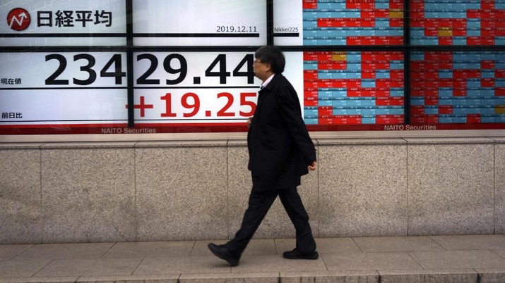 A man walks past an electronic stock board showing Japan's Nikkei 225 index at a securities firm in Tokyo Wednesday, Dec. 11, 2019. (AP Photo/Eugene Hoshiko)