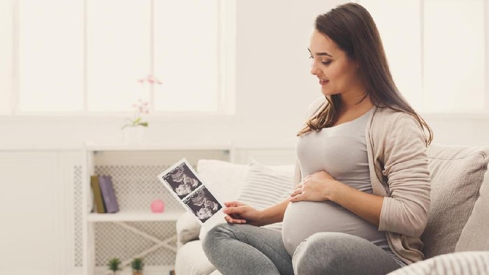 Pregnant woman looking at her baby sonography. Happy expectant lady enjoying first photo of her unborn child, anticipating her future life, copy space