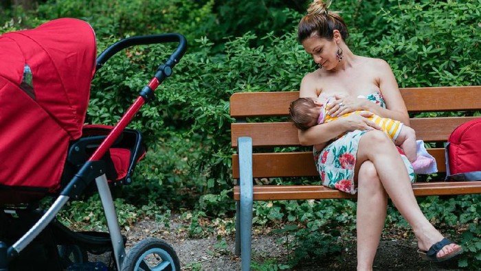 Young mom, playing and breastfeeding her toddler boy on board of aircraft, going on holiday
