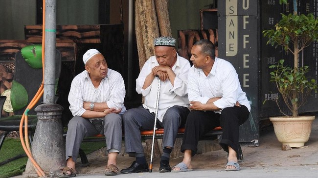 This photo taken on June 4, 2019 shows men resing in front of a coffee bar in the restored old city area of Kashgar, in China's western Xinjiang region. - In China's Xinjiang, a northwest region tightly controlled by police, authorities have created a parallel universe for tourists and locals -- a place where travellers sightsee just a stone's throw from internment camps. (Photo by GREG BAKER / AFP) / TO GO WITH: China-rights-tourism-Xinjiang, FEATURE by Eva XIAO