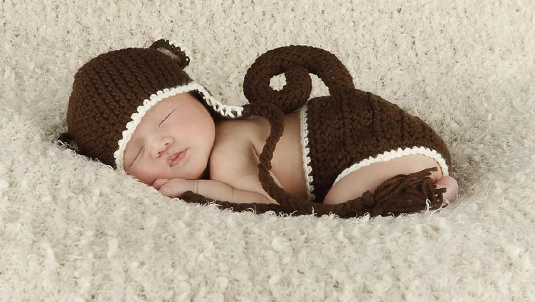 NB Newborn Asian baby in crochet monkey outfit.