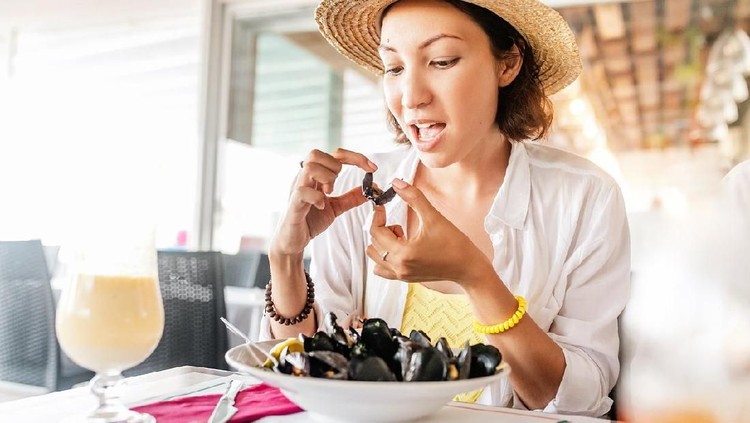 Close-up of woman eating mussel