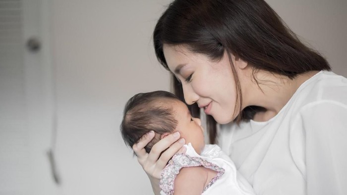 Beautiful woman holding a newborn baby in her arms