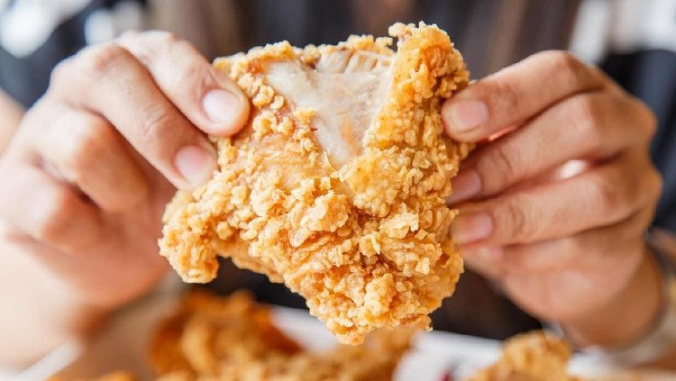 Hand holding Fried chicken and eating in the restaurant