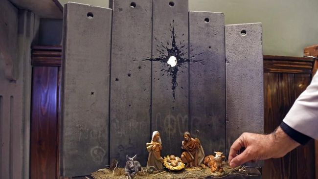 Jelang Natal, seniman misterius Banksy menyuguhkan karya mengenai kelahiran Kristus di Betlehem dengan latar tembok perbatasan Israel dengan Palestina.