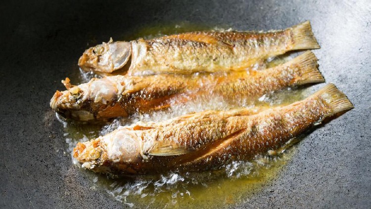Fried fish. Three fishes frying in hot oil in pan or skillet.