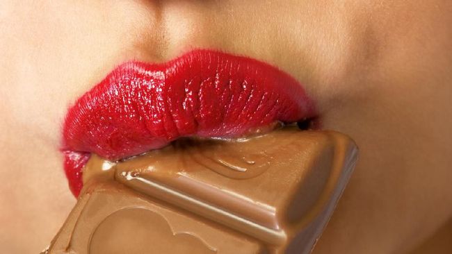 Closeup of young woman with chocolate in mouth