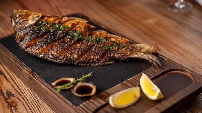 main dish in the restaurant. grilled grilled trout with lemon and lettuce leaves
