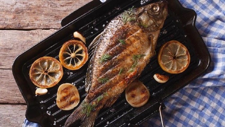 main dish in the restaurant. grilled grilled trout with lemon and lettuce leaves