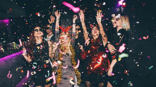Group of friends having fun for new year's eve in a club. Drinking and dancing together
