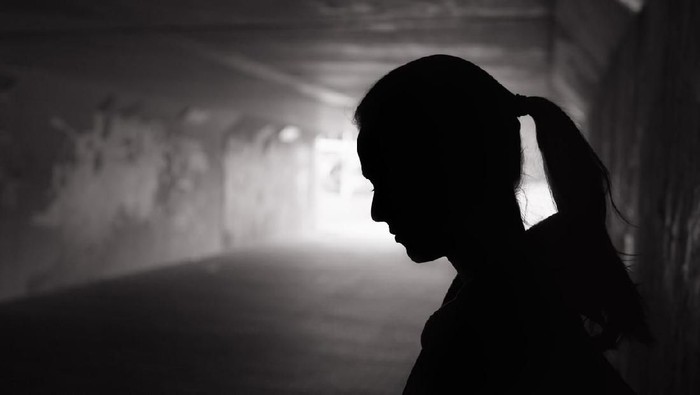 Depressed sad young female standing in a dark tunnel
