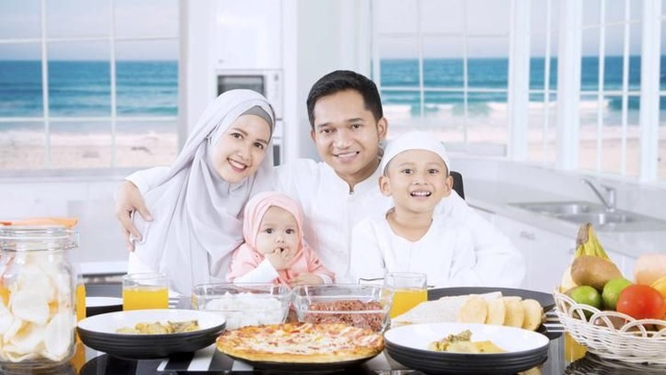 buka puasa Muslim parents and cute children smiling together in the kitchen with beach background on the window
