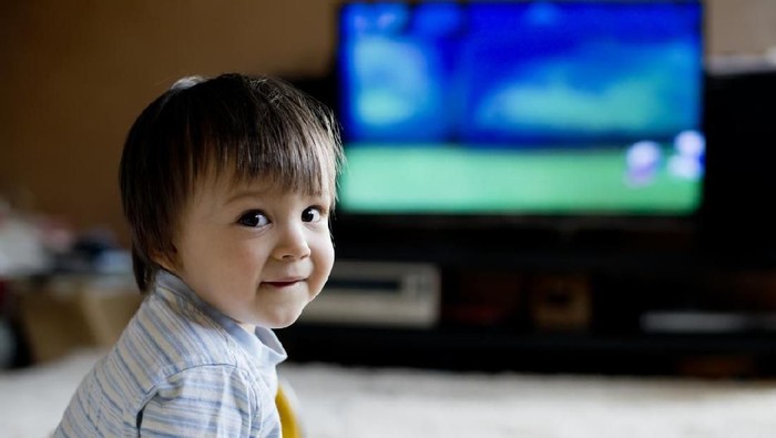 Little boy sitting on carpet and looking TV