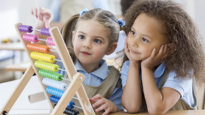 Happy schoolgirl preschool girl with book near school board blackboard