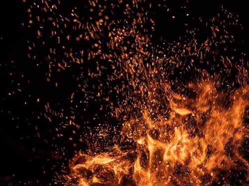 Burning sparks flying. Beautiful flames. Fiery orange glowing flying away particles on black background.