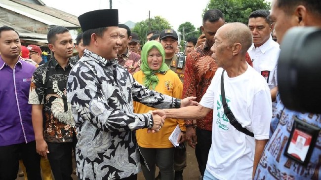 Seorang paruh baya (57) merangsek rombongan Tito Karnavian saat meninjau daerah terdampak banjir Bekasi. Dia minta bantuan Tito sediakan alat pembersih lumpur.