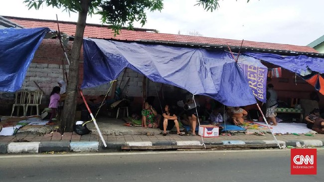 Warga Manggarai memilih tidur di tenda-tenda pengungsian pinggir jalan karena listrik rumah mereka masih padam sejak diterjang banjir Jakarta Rabu (1/1).