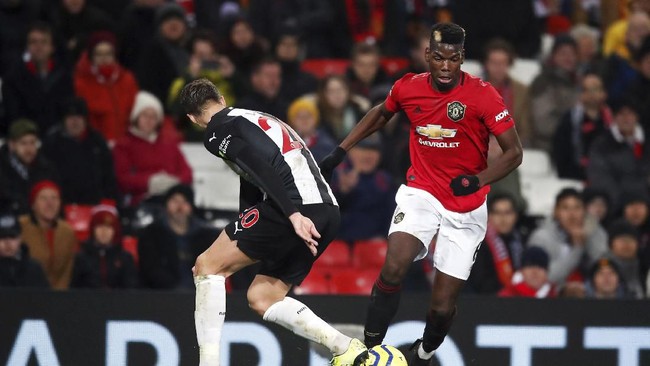Manchester United's Paul Pogba, right, and Newcastle United's Florian Lejeune battle for the ball during their English Premier League soccer match at Old Trafford, Manchester, England, Thursday, Dec. 26, 2019. (Martin Rickett/PA via AP)