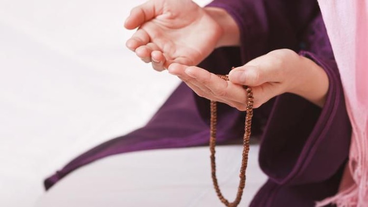 Young muslim girl with rosary praying on white background