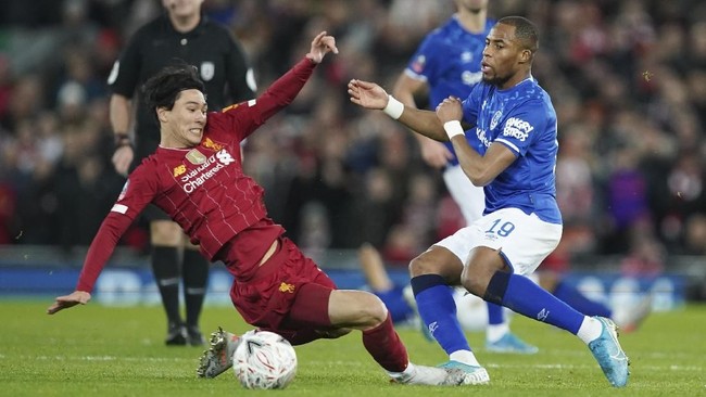 Liverpool's Takumi Minamino, left, challenges for the ball with Everton's Djibril Sidibe during the English FA Cup third round soccer match between Liverpool and Everton at Anfield stadium in Liverpool, England, Sunday, Jan. 5, 2020. (AP Photo/Jon Super)