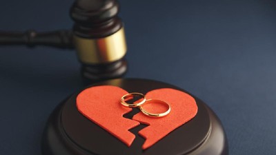 Wedding rings on the figure of a broken heart from a tree, hammer of a judge on a wooden background. Divorce proceedings
