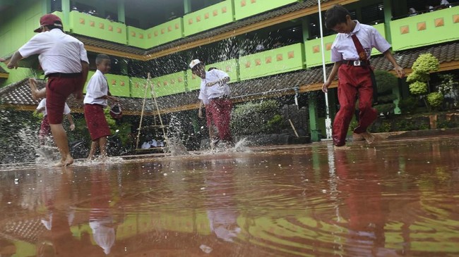 Siswa Sekolah Dasar Negeri Kapuk Muara 01 bermain air saat kerja bakti bersama pasca banjir di Jakarta, Senin (6/1/2019). Kegiatan belajar mengajar di sejumlah sekolah terdampak banjir belum efektif karena selain ruangan kelas terendam air juga digunakan sebagai tempat pengungsian. ANTARA FOTO/Muhammad Adimaja/ama.