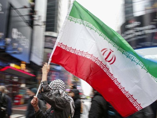 A man holds a Iranian flag during an anti-war protest, at Times Square in New York on January 4, 2020. - Demonstrators are protesting the US drone attack which killed Iran's Major General Qasem Soleimani in Iraq on January 3, a dramatic escalation in