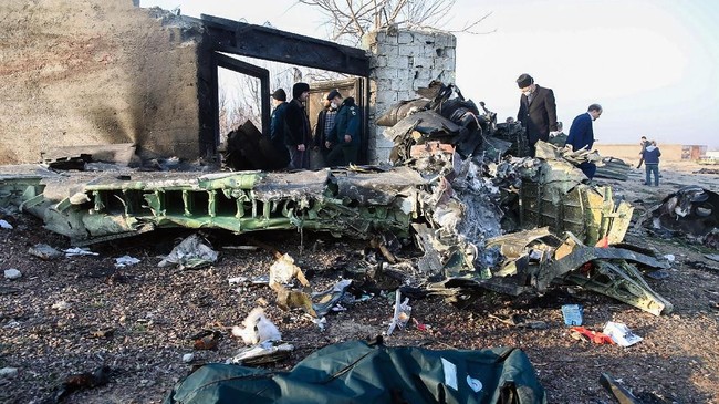 People stand near the wreckage after a Ukrainian plane carrying 176 passengers crashed near Imam Khomeini airport in Tehran on January 8, 2020. - All 176 people on board a Ukrainian passenger plane were killed when it crashed shortly after taking off from Tehran on January 8, Iranian state media reported. State news agency IRNA said 167 passengers and nine crew members were on board the aircraft operated by Ukraine International Airlines. (Photo by ROHHOLLAH VADATI / ISNA / AFP)