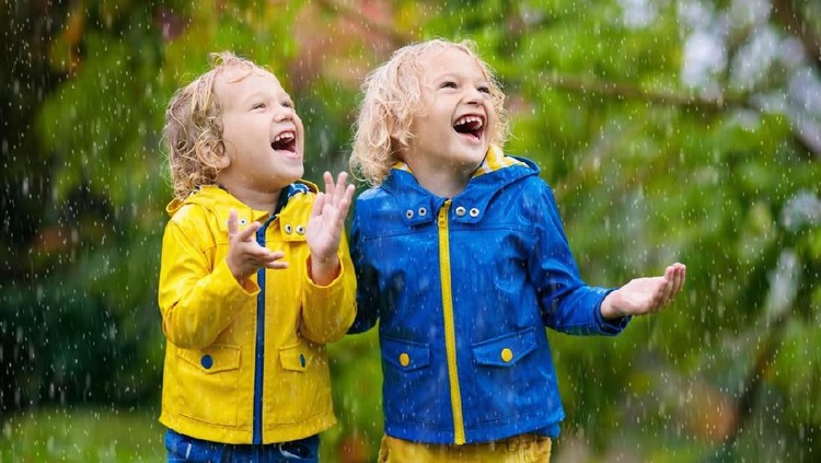 Kids play in autumn rain. Child playing outdoor on rainy day. Little boy catching rain drops under heavy shower. Fall storm in a park. Waterproof wear for kid. Children outdoors by any weather.