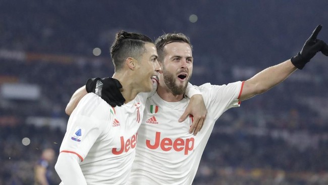 Juventus' Cristiano Ronaldo, left, celebrates with teammate Miralem Pjanic after scoring his side's second goal during the Serie A soccer match between Roma and Juventus at the Rome Olympic Stadium, Italy, Sunday, Jan. 12, 2020. (AP Photo/Andrew Medichini)