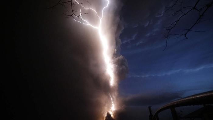 Lightning flashes as Taal Volcano erupts Sunday Jan. 12, 2020, in Tagaytay, Cavite province, outside Manila, Philippines.  A tiny volcano near the Philippine capital that draws many tourists for its picturesque setting in a lake belched steam, ash and rocks in a huge plume Sunday, prompting thousands of residents to flee and officials to temporarily suspend flights. (AP Photo/Aaron Favila)