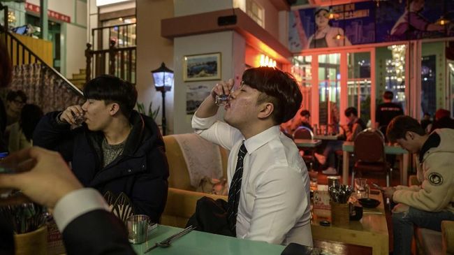 A photo taken on January 10, 2020 shows diners at the North Korean-themed Pyeongyang Bar in the Hongdae district of Seoul. - The Pyeongyang Bar is Seoul's only North Korean-themed bar and aims to give its South Korean patrons a taste of North Korean nightlife. Adorned with spoof propaganda slogans and imagery characteristic of the North, patrons can order typical North Korean dishes washed down with beverages bearing false North Korean brand labels -- which for now, due to trade and tourism blackout between the two countries, is the closest that most customers can expect to get to the real thing. (Photo by Ed JONES / AFP)