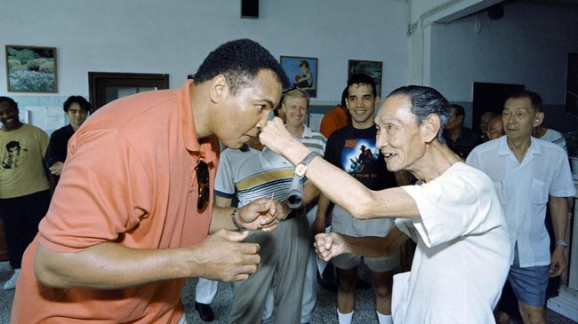 Boxing great Muhammad Ali receives a punch from a 79 old "sparring-partner" during a visit in a old people's home in Macau on September 1, 1994.   AFP PHOTO MIKE FIALA (Photo by MIKE FIALA / AFP)