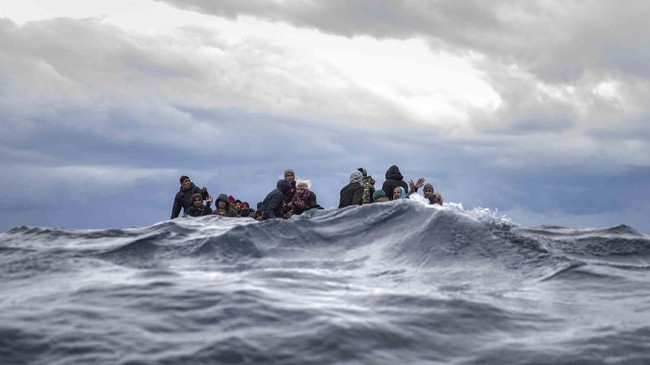 Men from Morocco and Bangladesh sit in an overcrowded wooden boat as aid workers of the Spanish NGO Open Arms approach them in the Mediterranean Sea, international waters, off the Libyan coast, Friday, Jan. 10, 2020. (AP Photo/Santi Palacios)