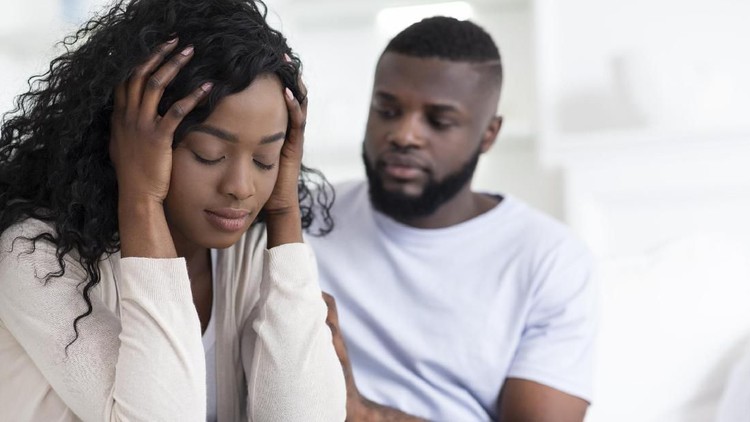 Loving african man soothing upset girlfriend, apologizing after quarrel, hugging her shoulder, empty space