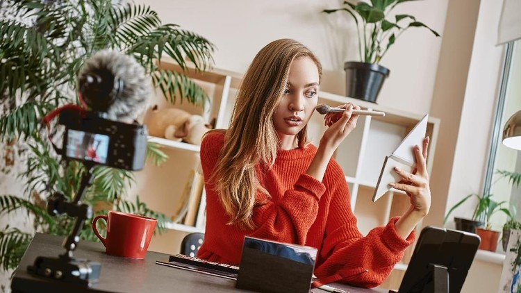 Makeup tutorial. Cute and young blogger using brush to apply highlighter while broadcasting live video to social network. Beauty tutorial. Blogging. Social Media